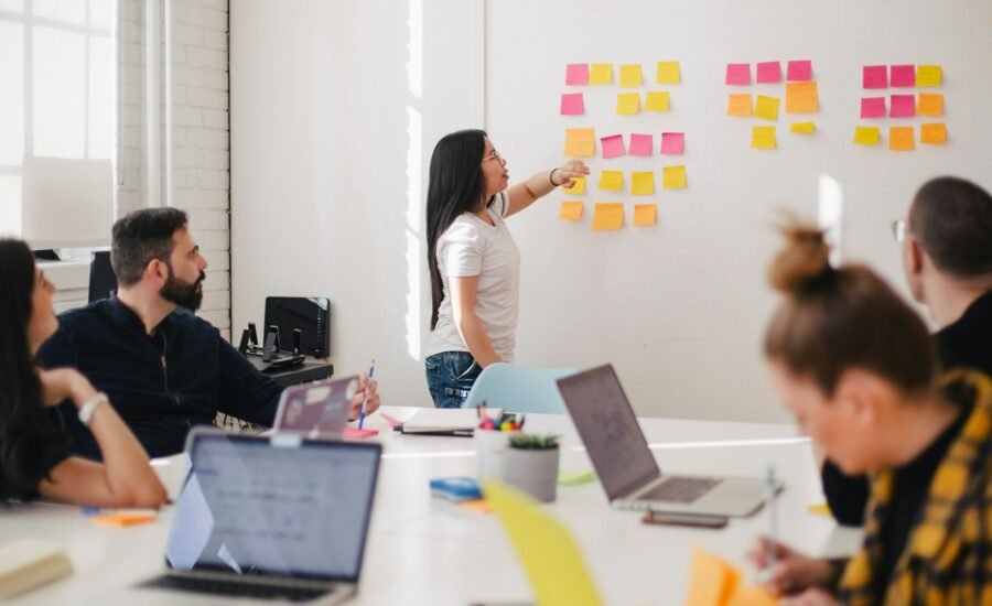 Business team mapping CRM follow-up workflows with sticky notes and laptops in a bright modern office