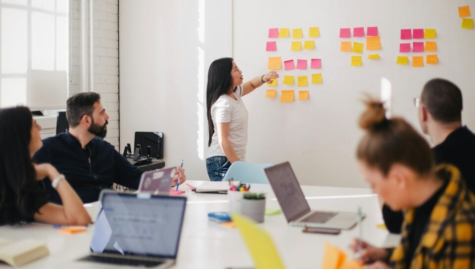 Business team mapping CRM follow-up workflows with sticky notes and laptops in a bright modern office