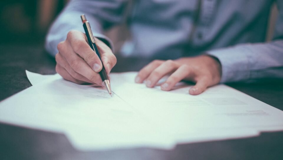AI Contract Review & NDA Redlining Workflows for UK & UAE SMEs (2026) Professional reviewing and signing business documents at a desk, representing AI-assisted contract review and NDA redlining